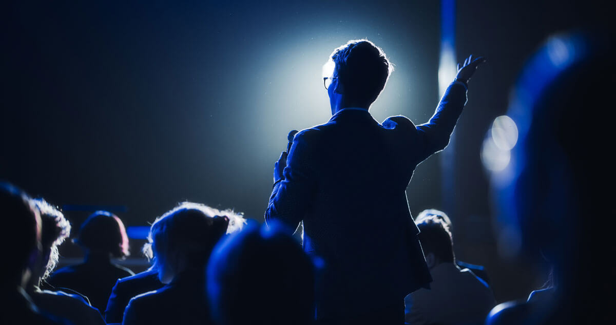 backlit man speaking to a crowd